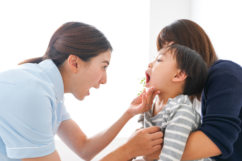 歯科衛生士に口腔内をチェックされる子ども